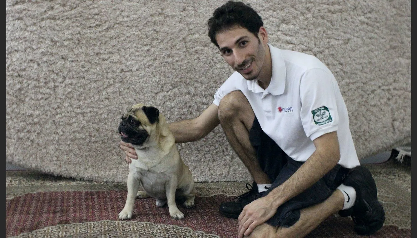 A shop technician standing among the rugs with the shop dog
