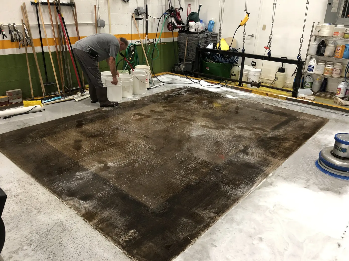 Large area rug laid flat on the wash floor, worked over with water and shampoo