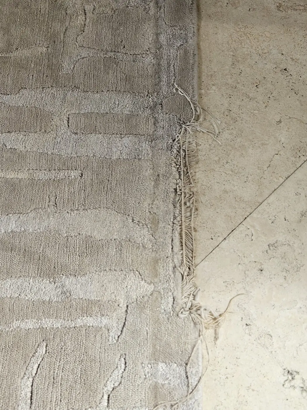 Worn end of a rug exposing the cotton foundation, noted at intake
